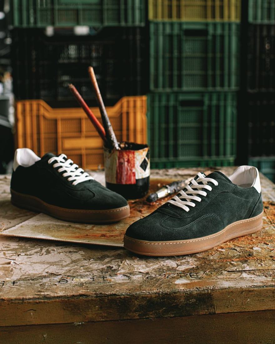Green suede sneakers on a workshop bench